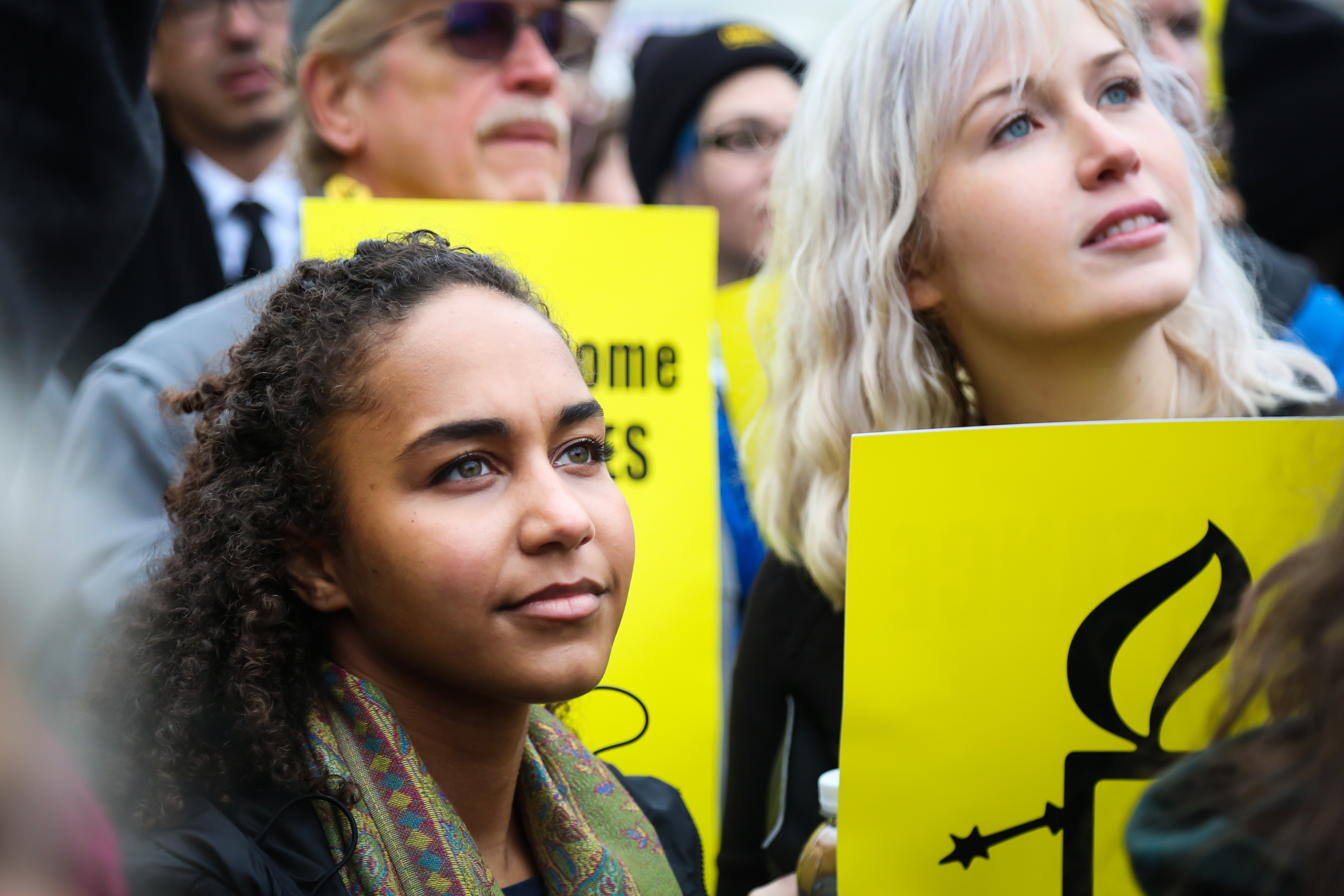 Bilde av to kvinner som deltar i en protest i USA. Den ene kvinnen holder en plakat med et Amnesty-lys. 