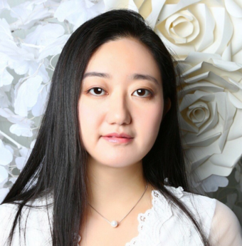 Li Qiaochu ser rett i kamera. Hun har langt, svart hår og har på seg en hvit blondebluse og et enkelt halskjede med en perle på. 
