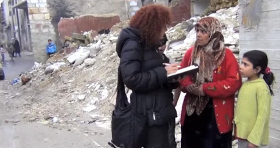 Amnestys etterforsker Donatella snakker med en kvinne og et barn i et krigsrammet område. 