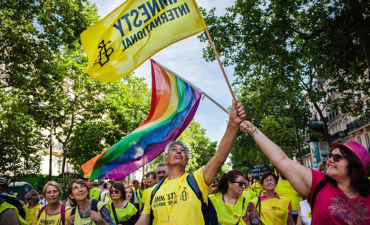 Mennesker feirer Pride med både regnbueflagg og Amnesty-flagg.