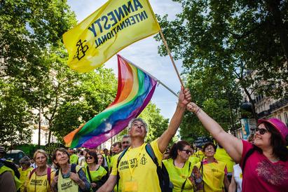 Mennesker feirer Pride med både regnbueflagg og Amnesty-flagg.
