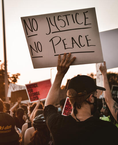 Person holder en plakat med teksten "No justice no peace"