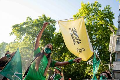 Kvinne vifter Amnesty-flagg under en demonstrasjon.