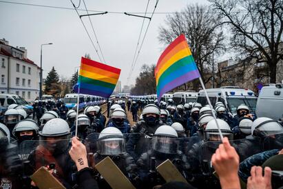 Demonstrasjon i Polen - regnblueflagg holdes opp foran politi med hjem og skjold