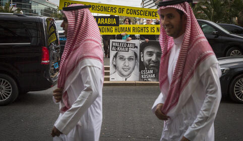 To menn fra Saudi-Arabia går forbi en Amnesty-demonstrasjon utenfor en ambassadefest i Scheveningen. 