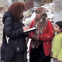 Amnestys etterforsker Donatella snakker med en kvinne og et barn i et krigsrammet område. 